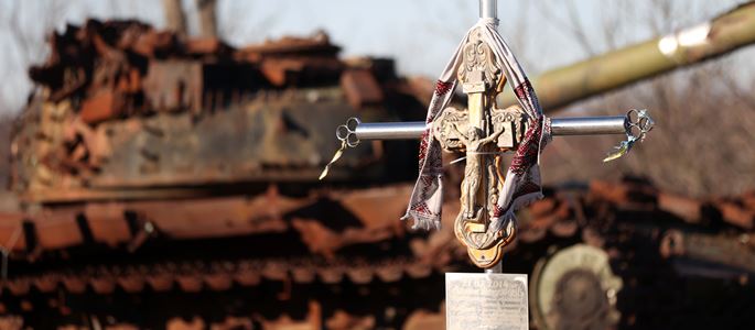 Ein Kreuz mit einem Panzer im Hintergrund