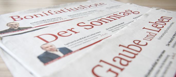 Drei Zeitungen auf einem Tisch.